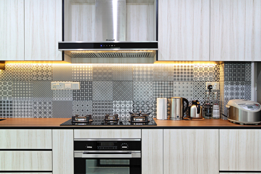 シンガポールにある北欧スタイルのおしゃれなキッチン (フラットパネル扉のキャビネット、淡色木目調キャビネット、木材カウンター、黒いキッチンパネル) の写真