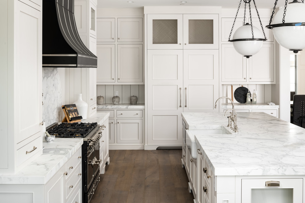 Idéer för att renovera ett lantligt vit vitt l-kök, med en rustik diskho, luckor med infälld panel, vita skåp, vitt stänkskydd, svarta vitvaror, mörkt trägolv, en köksö och brunt golv