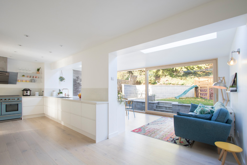 This is an example of a large modern l-shaped open plan kitchen in Gloucestershire with flat-panel cabinets, white cabinets, composite countertops, beige splashback, no island and beige worktops.
