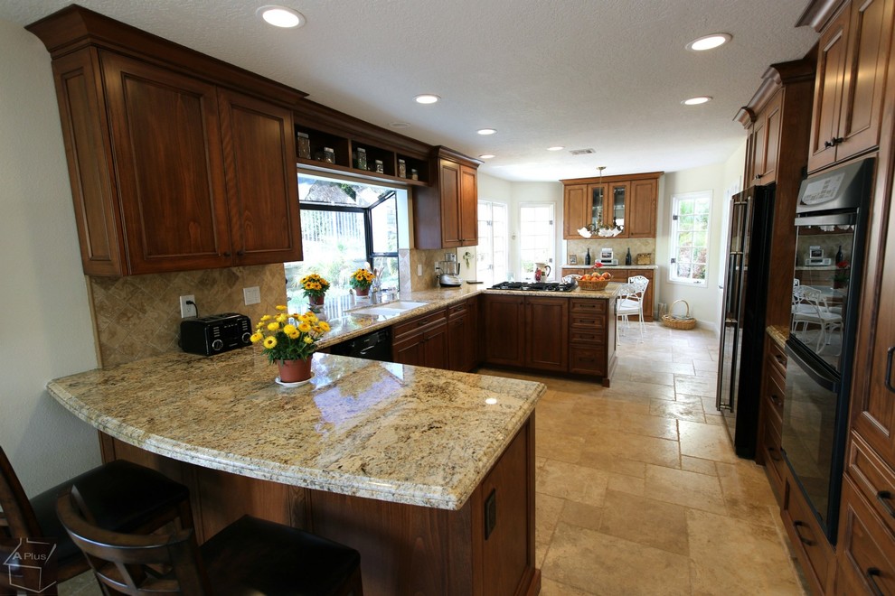 Bild på ett mellanstort vintage kök, med en dubbel diskho, luckor med infälld panel, skåp i mellenmörkt trä, granitbänkskiva, brunt stänkskydd, stänkskydd i stenkakel, svarta vitvaror, klinkergolv i porslin och en halv köksö