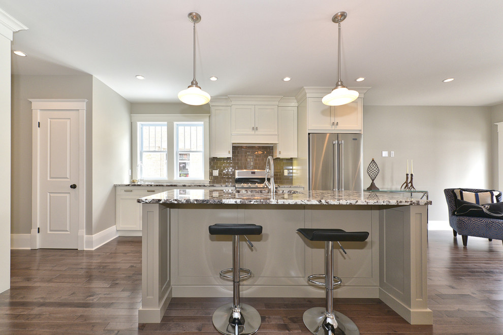 Mid-sized transitional galley medium tone wood floor and brown floor open concept kitchen photo in Toronto with an undermount sink, shaker cabinets, white cabinets, granite countertops, brown backsplash, subway tile backsplash, stainless steel appliances and an island