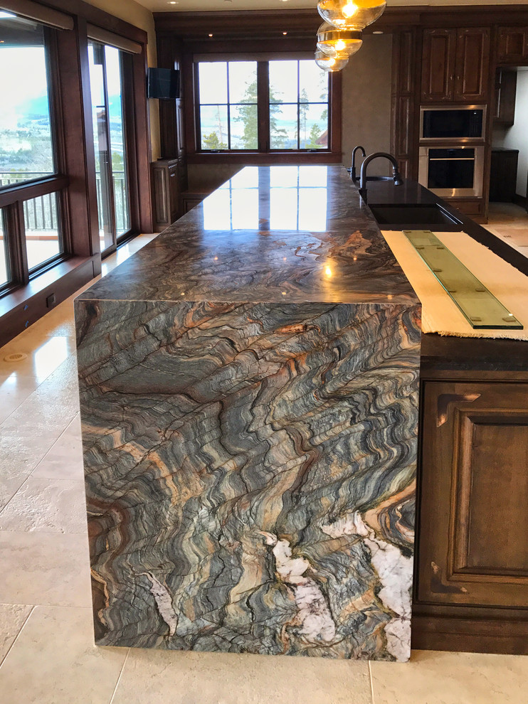 Cette photo montre une grande cuisine américaine avec un plan de travail en granite, une crédence bleue, une crédence en mosaïque, un électroménager en acier inoxydable, un sol en travertin, îlot et un sol beige.