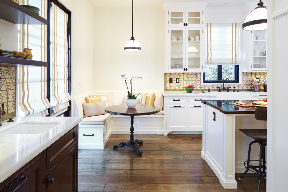 Exempel på ett mellanstort klassiskt kök, med en rustik diskho, luckor med glaspanel, vita skåp, bänkskiva i kalksten, gult stänkskydd, stänkskydd i mosaik, svarta vitvaror, mellanmörkt trägolv, en köksö och brunt golv