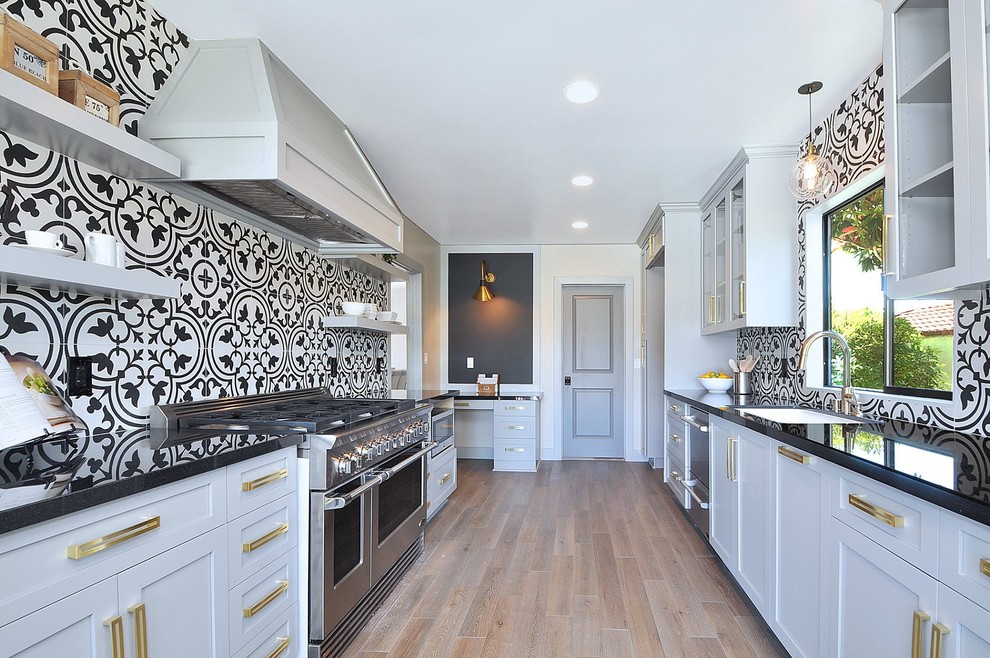 Klassische Küche ohne Insel mit Unterbauwaschbecken, Schrankfronten im Shaker-Stil, grauen Schränken, bunter Rückwand, Küchengeräten aus Edelstahl und braunem Holzboden in Los Angeles