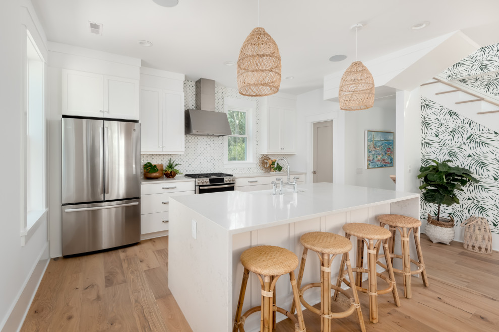 Foto på ett stort tropiskt vit linjärt kök med öppen planlösning, med en rustik diskho, skåp i shakerstil, vita skåp, bänkskiva i kvarts, grönt stänkskydd, stänkskydd i marmor, rostfria vitvaror, ljust trägolv och en köksö