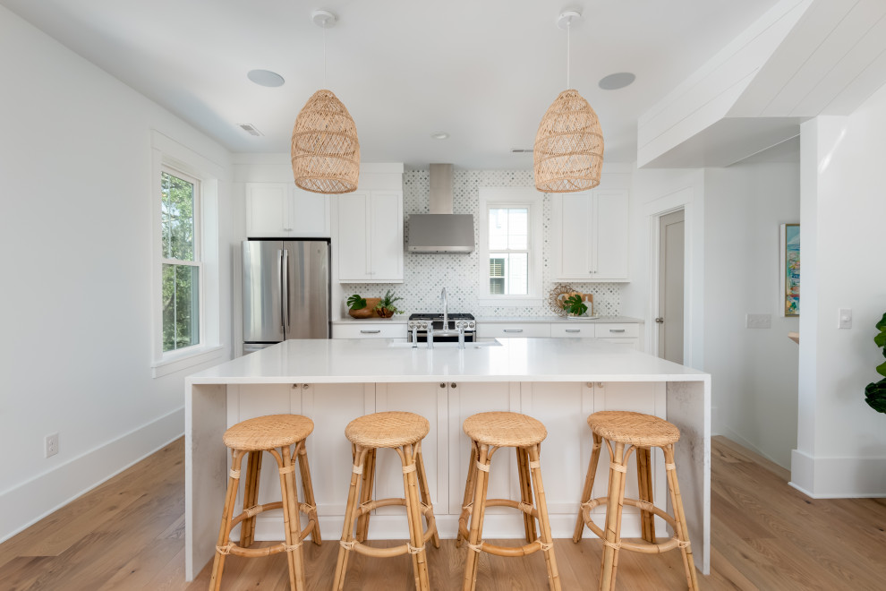 Inspiration for a large tropical single-wall light wood floor open concept kitchen remodel in Charleston with a farmhouse sink, shaker cabinets, white cabinets, quartz countertops, green backsplash, marble backsplash, stainless steel appliances, an island and white countertops