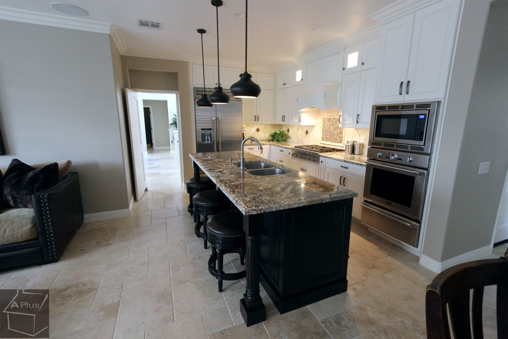 Eat-in kitchen - mid-sized traditional l-shaped porcelain tile eat-in kitchen idea in Orange County with a double-bowl sink, recessed-panel cabinets, white cabinets, granite countertops, beige backsplash, stone tile backsplash, stainless steel appliances and an island