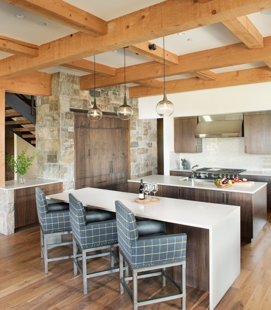 This is an example of a rustic kitchen in Other with flat-panel cabinets, dark wood cabinets, white splashback, metro tiled splashback, medium hardwood flooring, multiple islands, white worktops, a coffered ceiling and exposed beams.