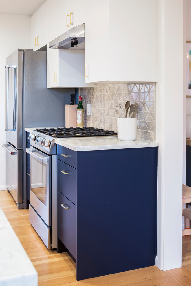 Medium sized modern galley enclosed kitchen in Seattle with flat-panel cabinets, blue cabinets, quartz worktops, grey splashback, ceramic splashback, stainless steel appliances and light hardwood flooring.