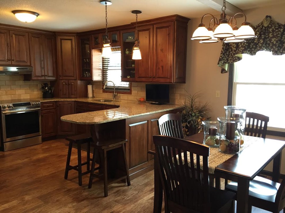 Example of a mid-sized classic u-shaped eat-in kitchen design in Minneapolis with an undermount sink, raised-panel cabinets, dark wood cabinets, granite countertops, beige backsplash, subway tile backsplash, stainless steel appliances and a peninsula