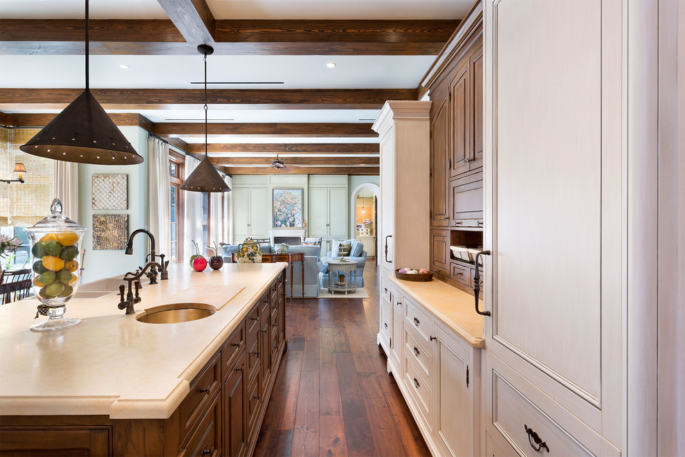 Example of a mid-sized tuscan l-shaped medium tone wood floor and brown floor open concept kitchen design in Miami with an undermount sink, recessed-panel cabinets, light wood cabinets, solid surface countertops, brown backsplash, wood backsplash, stainless steel appliances, an island and beige countertops
