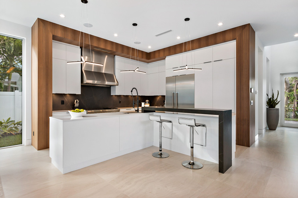 Mid-sized trendy l-shaped beige floor kitchen photo in Miami with an undermount sink, flat-panel cabinets, white cabinets, black backsplash, porcelain backsplash, stainless steel appliances, two islands and white countertops