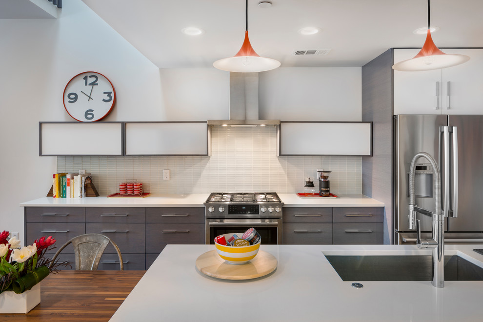 Exempel på ett mellanstort modernt linjärt kök och matrum, med släta luckor, grå skåp, bänkskiva i kvarts, vitt stänkskydd, stänkskydd i tunnelbanekakel, rostfria vitvaror och en köksö