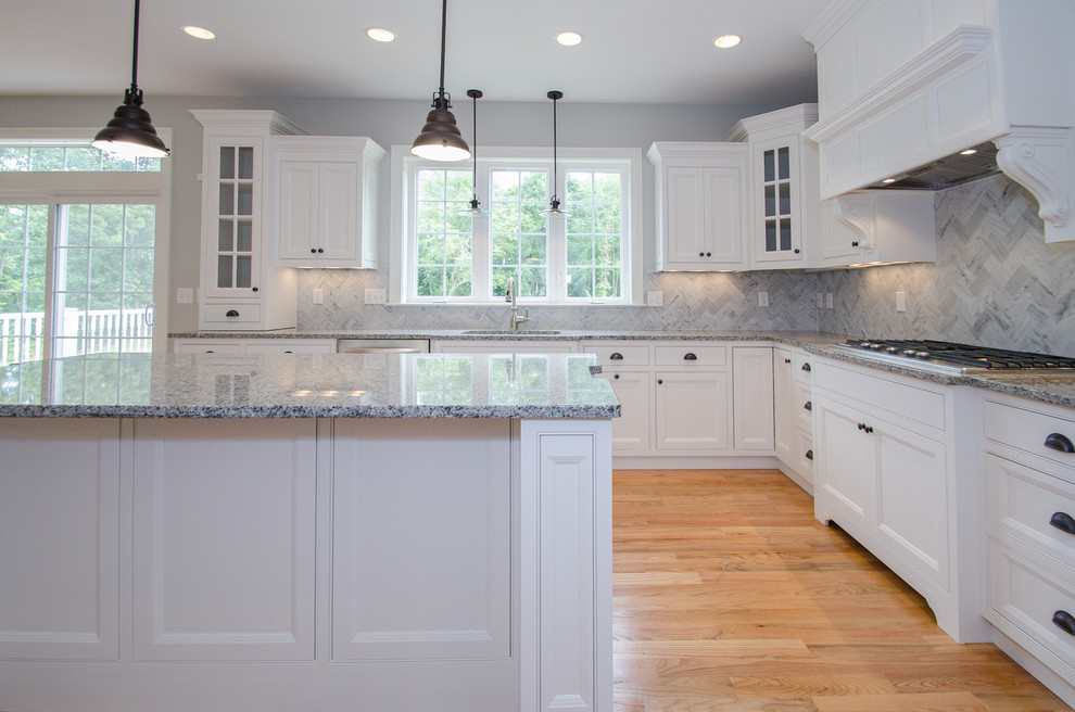 Inspiration for a mid-sized transitional u-shaped light wood floor eat-in kitchen remodel in Bridgeport with an undermount sink, beaded inset cabinets, white cabinets, granite countertops, gray backsplash, stone tile backsplash, stainless steel appliances and an island