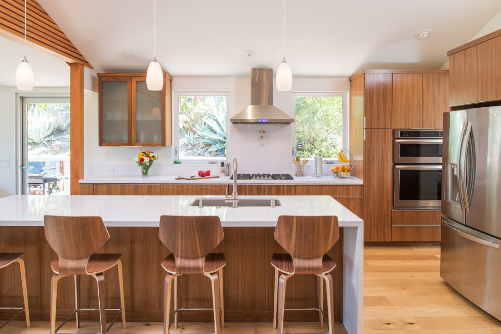 サンディエゴにある高級な広いコンテンポラリースタイルのおしゃれなキッチン (ダブルシンク、フラットパネル扉のキャビネット、中間色木目調キャビネット、クオーツストーンカウンター、白いキッチンパネル、シルバーの調理設備、無垢フローリング) の写真