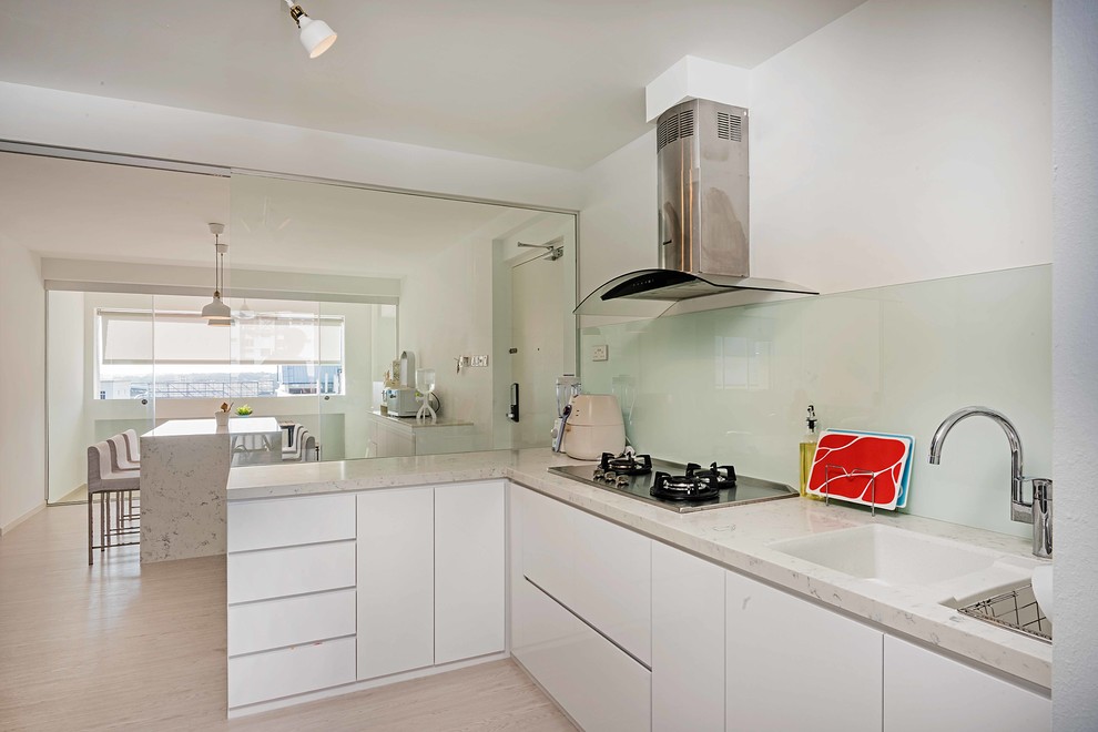 Photo of a scandi l-shaped kitchen in Singapore with a submerged sink, flat-panel cabinets, white cabinets, white splashback, glass sheet splashback, integrated appliances, light hardwood flooring, no island, beige floors and beige worktops.