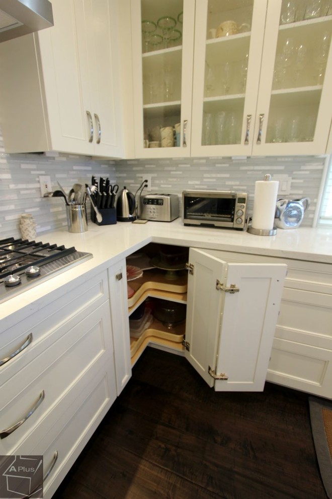 Example of a large beach style l-shaped dark wood floor eat-in kitchen design in Orange County with a double-bowl sink, recessed-panel cabinets, white cabinets, quartzite countertops, white backsplash, mosaic tile backsplash, stainless steel appliances and an island