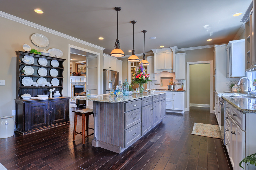 Large country u-shaped dark wood floor open concept kitchen photo in Other with a farmhouse sink, white cabinets, granite countertops, white backsplash, paneled appliances and an island