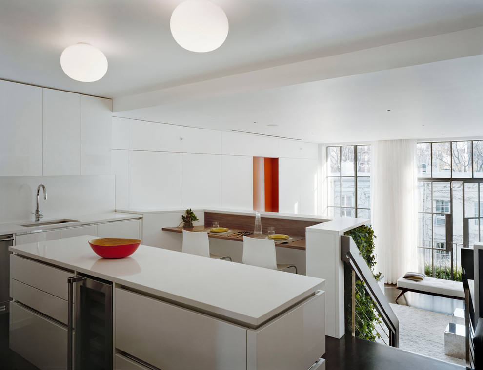 Inredning av ett modernt stort kök och matrum, med betonggolv, en undermonterad diskho, vitt stänkskydd, rostfria vitvaror, släta luckor, vita skåp och en köksö