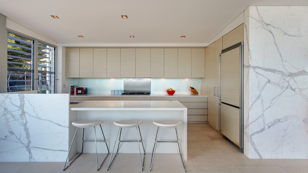 Moderne Küche mit flächenbündigen Schrankfronten, hellen Holzschränken und Glasrückwand in Sydney