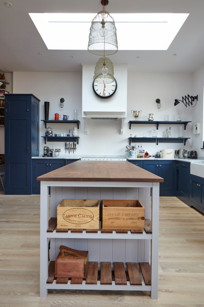 Offene, Mittelgroße Klassische Küche in L-Form mit Schrankfronten im Shaker-Stil, blauen Schränken, Arbeitsplatte aus Holz, hellem Holzboden und Kücheninsel in Surrey