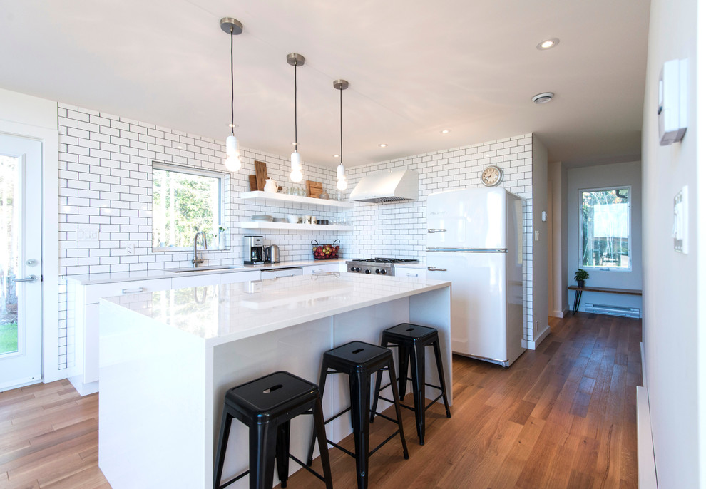 Inspiration for a mid-sized modern l-shaped light wood floor eat-in kitchen remodel in Other with an undermount sink, flat-panel cabinets, white cabinets, quartzite countertops, white backsplash, subway tile backsplash, white appliances and an island