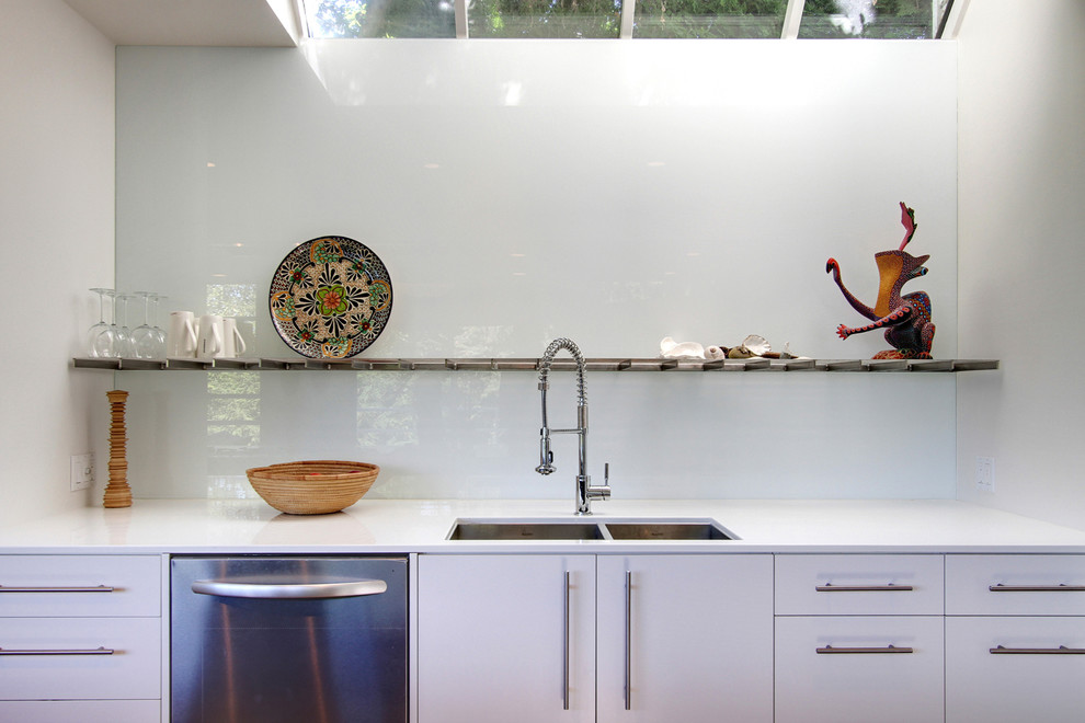 Imagen de cocina contemporánea con fregadero de doble seno, armarios con paneles lisos, puertas de armario blancas, salpicadero de vidrio templado y electrodomésticos de acero inoxidable