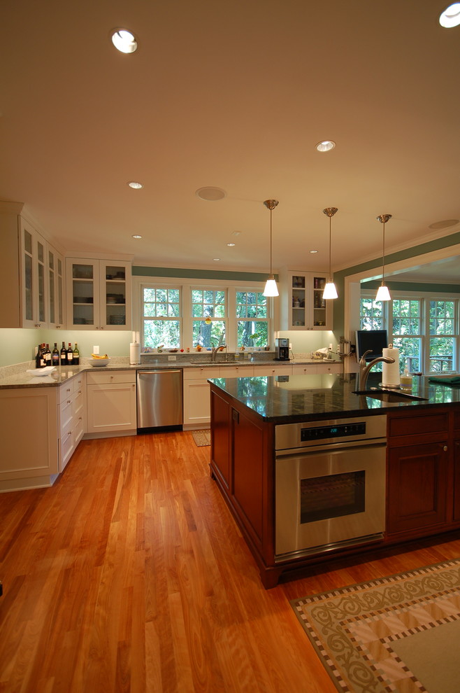 Bild på ett mycket stort vintage kök med öppen planlösning, med en undermonterad diskho, luckor med infälld panel, vita skåp, rostfria vitvaror, mellanmörkt trägolv, en köksö, granitbänkskiva, grått stänkskydd och stänkskydd i sten