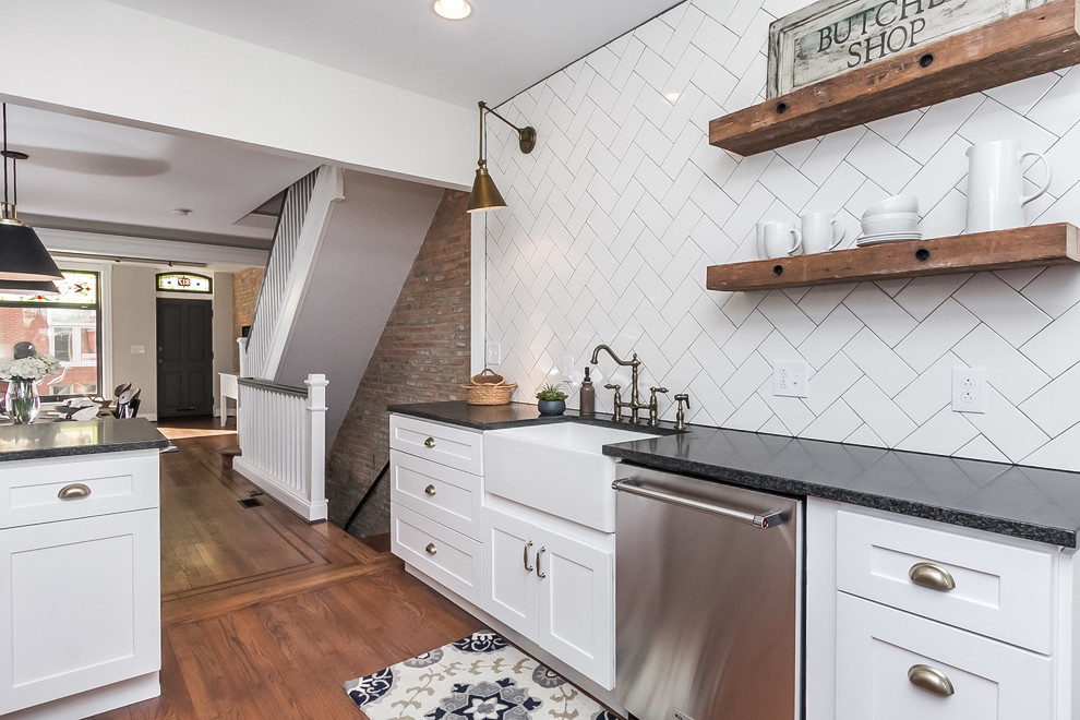 Photo of a large urban open plan kitchen in Baltimore with a submerged sink, shaker cabinets, white cabinets, engineered stone countertops, white splashback, metro tiled splashback, stainless steel appliances, medium hardwood flooring, a breakfast bar and brown floors.
