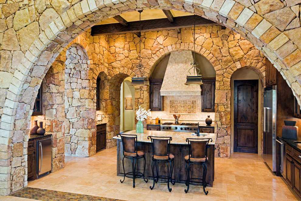 Immagine di una cucina a L mediterranea con ante con bugna sagomata, ante in legno bruno e elettrodomestici in acciaio inossidabile