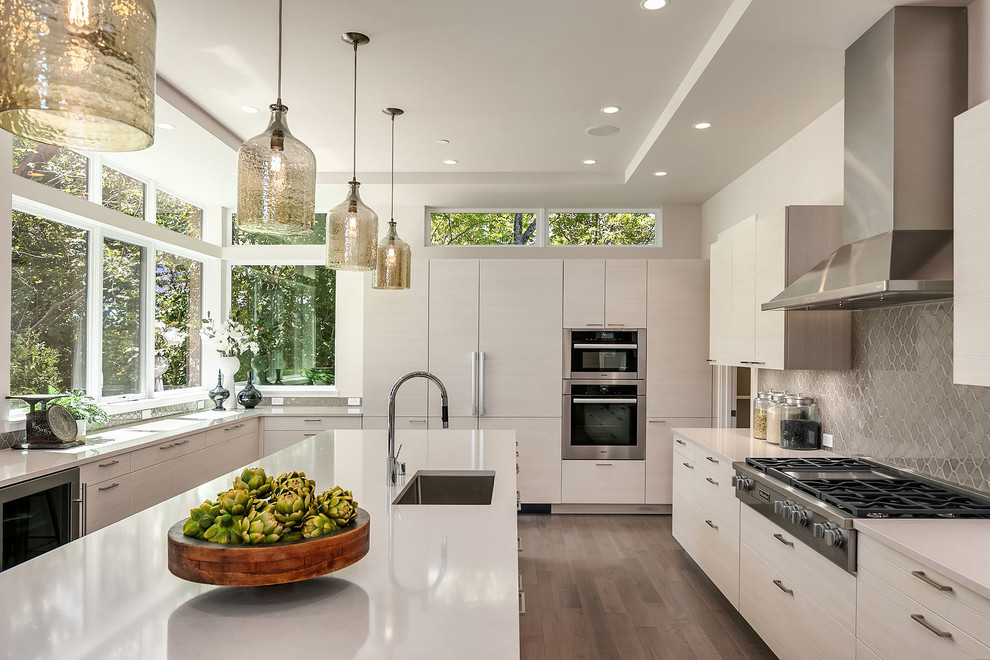 Photo of a contemporary u-shaped enclosed kitchen in Seattle with a submerged sink, grey splashback, stainless steel appliances, light hardwood flooring, brown floors and beige worktops.