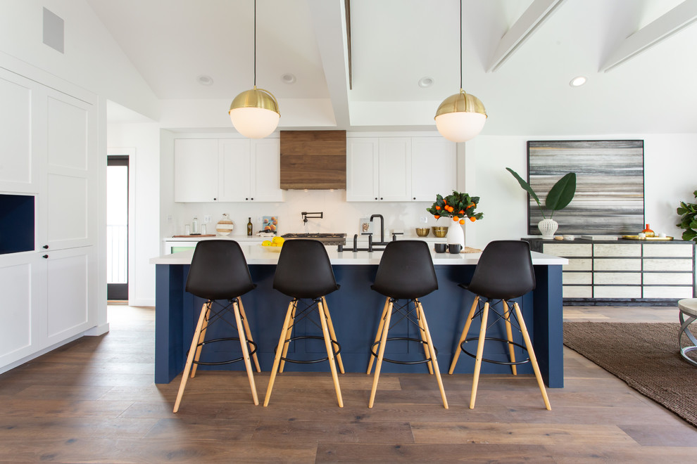 Transitional dark wood floor and brown floor open concept kitchen photo in Los Angeles with an undermount sink, shaker cabinets, white cabinets, white backsplash, an island and white countertops