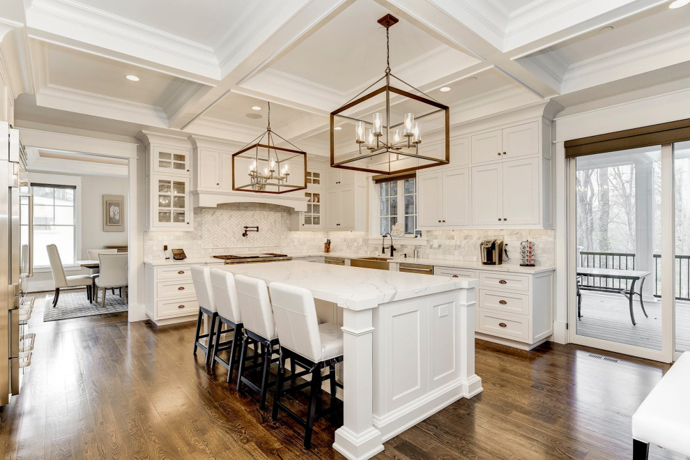 This is an example of a classic u-shaped enclosed kitchen in DC Metro with a belfast sink, recessed-panel cabinets, white cabinets, marble worktops, grey splashback, metro tiled splashback, stainless steel appliances, medium hardwood flooring, an island, brown floors and a coffered ceiling.