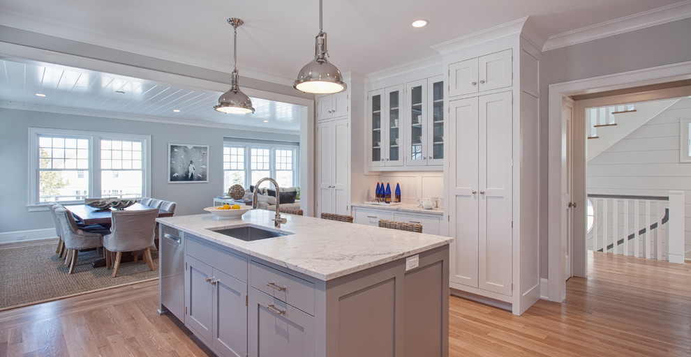 Eat-in kitchen - large coastal u-shaped light wood floor and brown floor eat-in kitchen idea in Other with an undermount sink, recessed-panel cabinets, white cabinets, marble countertops, gray backsplash, ceramic backsplash, stainless steel appliances and an island