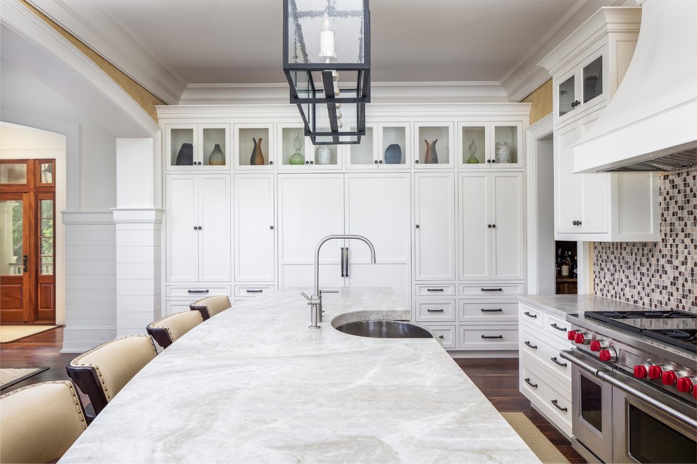 Foto på ett stort maritimt vit linjärt kök med öppen planlösning, med en undermonterad diskho, luckor med infälld panel, vita skåp, granitbänkskiva, flerfärgad stänkskydd, stänkskydd i keramik, integrerade vitvaror, mörkt trägolv, en köksö och brunt golv