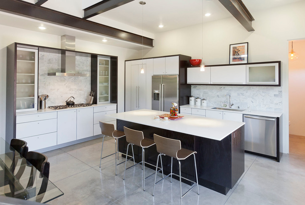 Inspiration for a large contemporary l-shaped kitchen/diner in Albuquerque with a submerged sink, flat-panel cabinets, white cabinets, engineered stone countertops, white splashback, stone slab splashback, stainless steel appliances, medium hardwood flooring and an island.