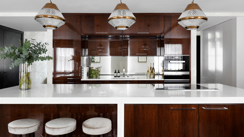 Cette image montre une grande cuisine américaine minimaliste en bois brun avec un évier intégré, un placard à porte plane, plan de travail en marbre, une crédence miroir, un électroménager noir, parquet clair et îlot.