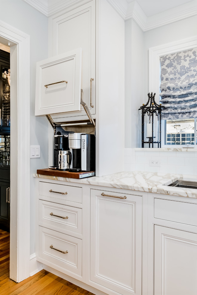 Foto på ett avskilt, mellanstort vintage vit kök, med en undermonterad diskho, luckor med profilerade fronter, vita skåp, marmorbänkskiva, vitt stänkskydd, stänkskydd i tunnelbanekakel, rostfria vitvaror, mellanmörkt trägolv och brunt golv