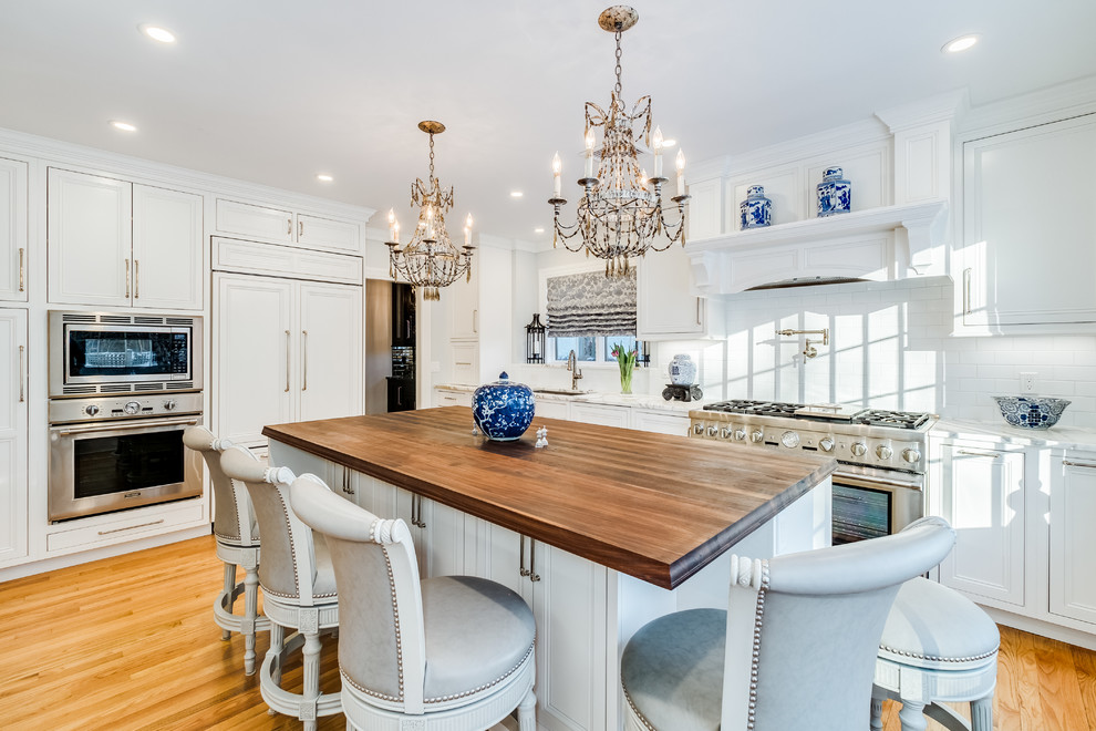 Mid-sized elegant single-wall medium tone wood floor and brown floor enclosed kitchen photo in Bridgeport with an undermount sink, beaded inset cabinets, white cabinets, marble countertops, white backsplash, subway tile backsplash, stainless steel appliances, an island and white countertops