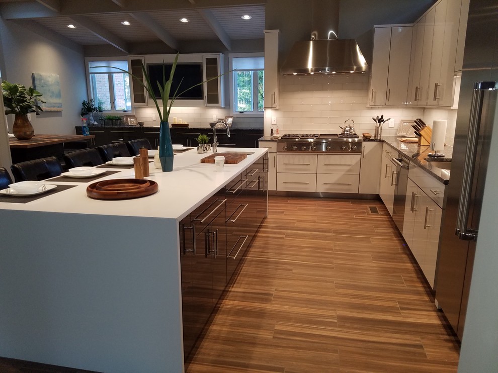 Design ideas for a medium sized midcentury l-shaped kitchen/diner in Raleigh with a single-bowl sink, flat-panel cabinets, grey cabinets, engineered stone countertops, white splashback, glass tiled splashback, stainless steel appliances, porcelain flooring and an island.