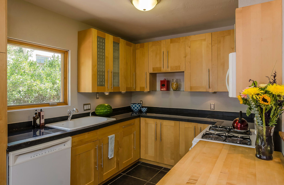 Amerikansk inredning av ett litet kök, med en enkel diskho, skåp i shakerstil, skåp i ljust trä, granitbänkskiva, grått stänkskydd, vita vitvaror och skiffergolv