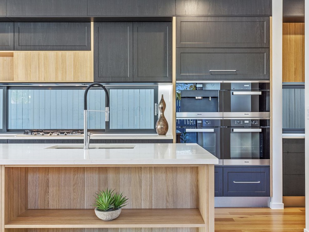 Photo of a large contemporary kitchen/diner in Brisbane with dark wood cabinets, composite countertops, window splashback, stainless steel appliances and an island.