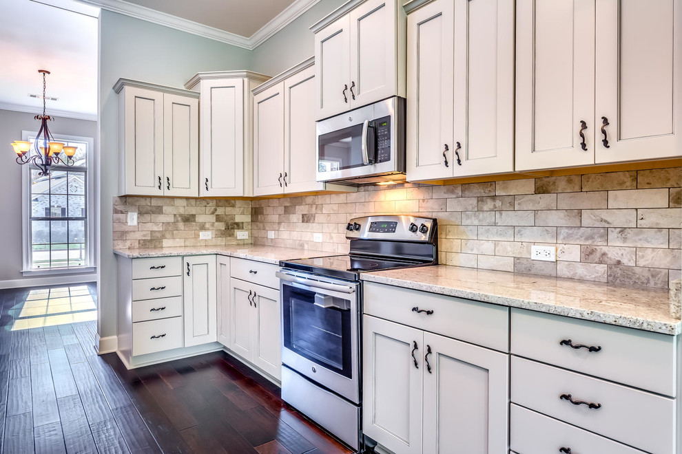 Mid-sized elegant galley dark wood floor eat-in kitchen photo in Other with a drop-in sink, raised-panel cabinets, beige cabinets, granite countertops, brown backsplash, stone tile backsplash and stainless steel appliances