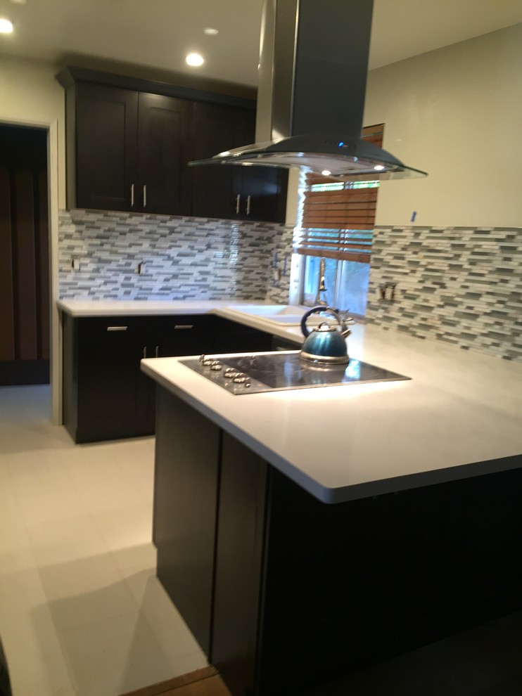 This is an example of a small classic u-shaped kitchen in Los Angeles with a built-in sink, shaker cabinets, dark wood cabinets, quartz worktops, grey splashback, matchstick tiled splashback, stainless steel appliances and a breakfast bar.