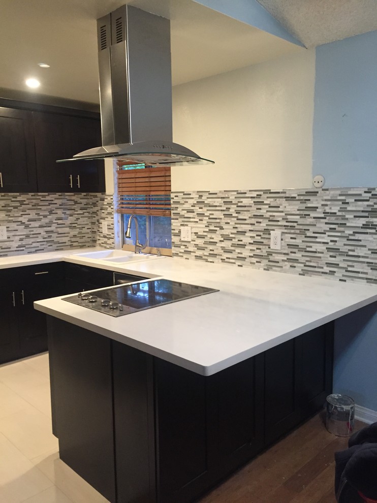 Example of a small transitional u-shaped kitchen design in Los Angeles with a drop-in sink, shaker cabinets, dark wood cabinets, quartzite countertops, gray backsplash, matchstick tile backsplash, stainless steel appliances and a peninsula