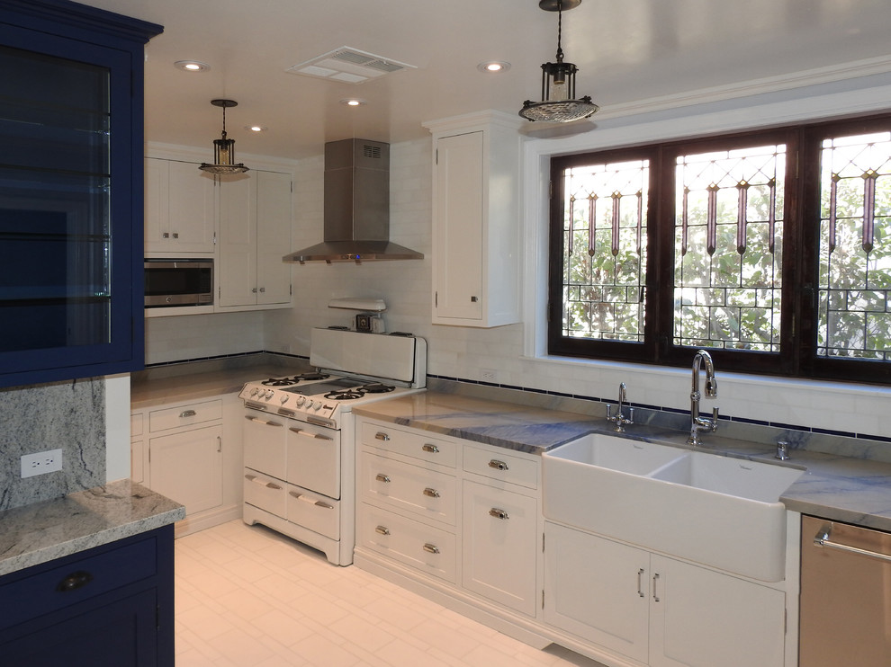 This is an example of a medium sized traditional l-shaped enclosed kitchen in Los Angeles with a belfast sink, white cabinets, quartz worktops, white splashback, marble splashback, white appliances, marble flooring, an island, white floors, blue worktops and shaker cabinets.