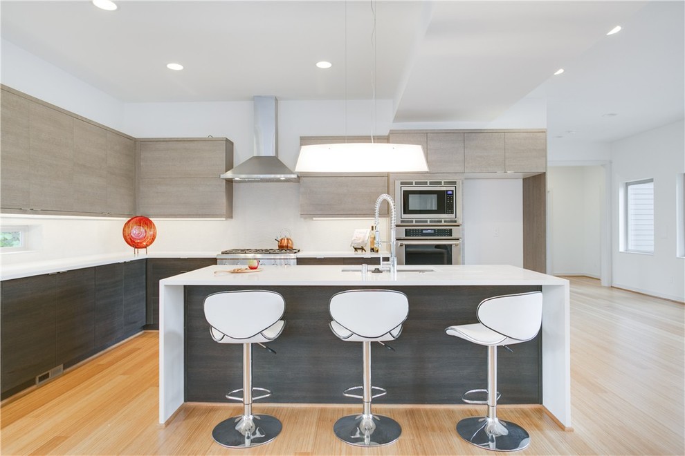 Foto de cocinas en L moderna abierta con armarios con paneles lisos, electrodomésticos de acero inoxidable y una isla