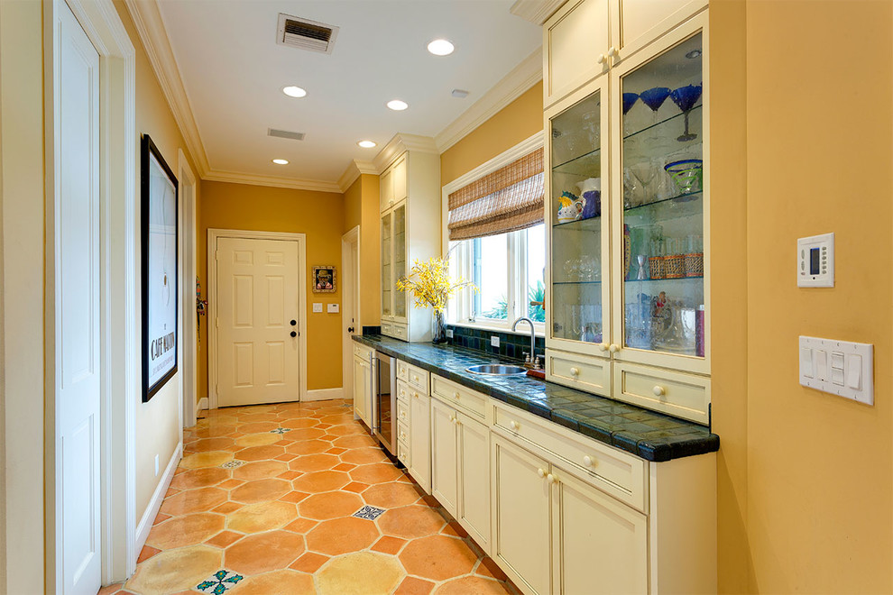 Bild på ett avskilt, mellanstort tropiskt flerfärgad linjärt flerfärgat kök, med en undermonterad diskho, luckor med infälld panel, vita skåp, kaklad bänkskiva, flerfärgad stänkskydd, stänkskydd i mosaik, rostfria vitvaror, flerfärgat golv och klinkergolv i terrakotta