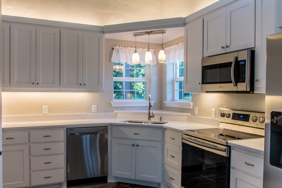 Foto di una cucina classica di medie dimensioni con lavello sottopiano, ante in stile shaker, ante bianche, top in quarzite, elettrodomestici in acciaio inossidabile, parquet scuro e pavimento marrone