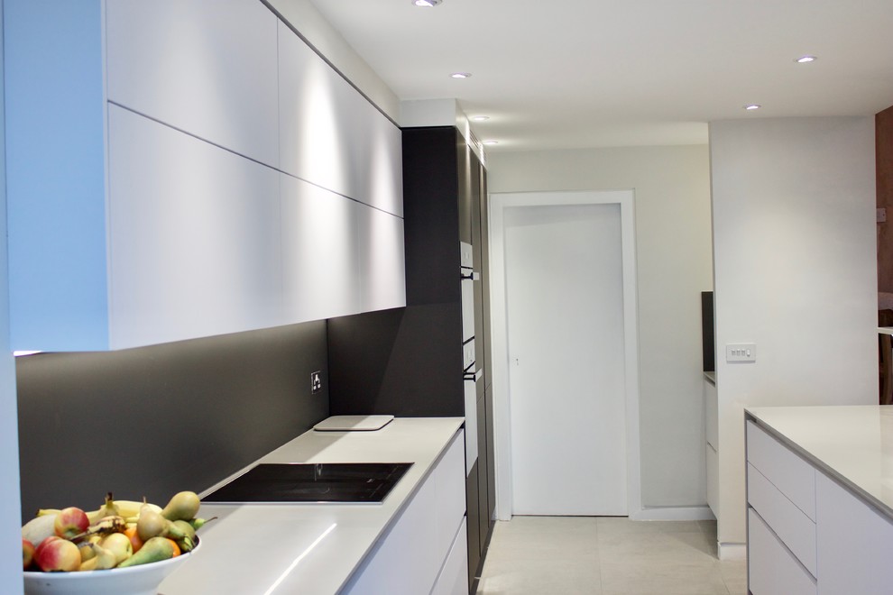 This is an example of a large modern galley kitchen/diner in Other with a built-in sink, flat-panel cabinets, white cabinets, composite countertops, grey splashback, glass sheet splashback, black appliances, ceramic flooring and a breakfast bar.